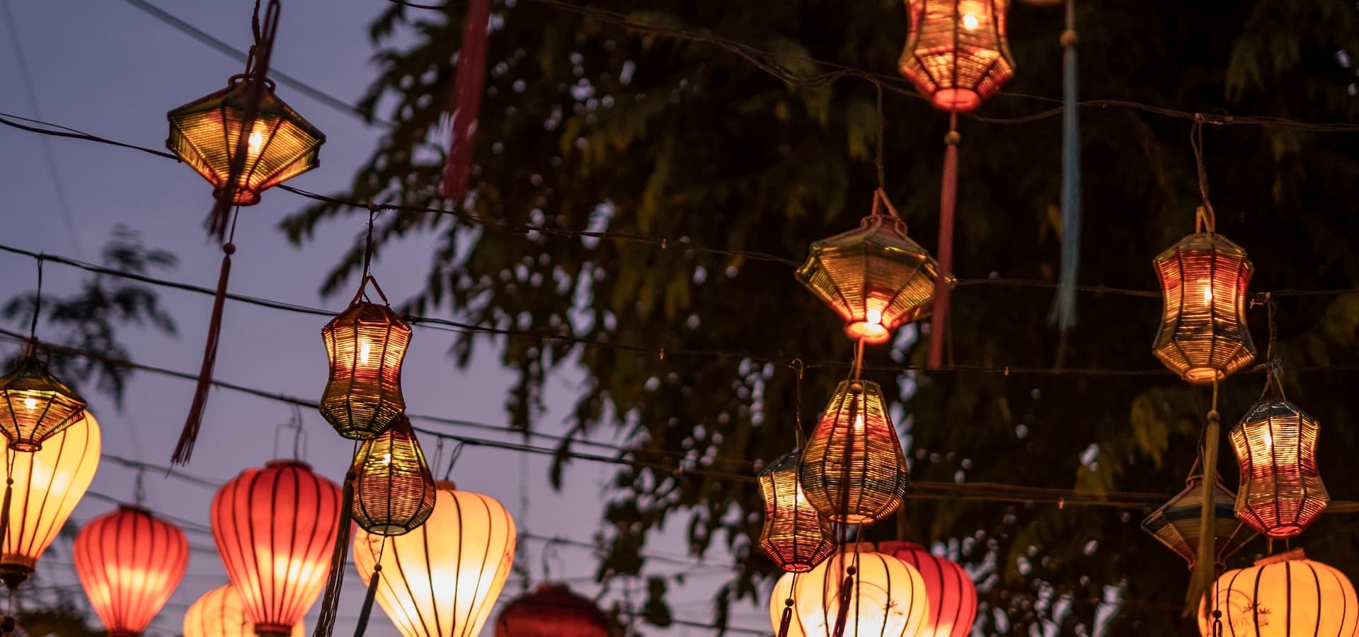 Silk lanterns glowing over a Hội An street at dusk